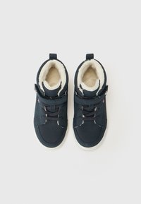 Marineblaue Wildlederschuhe mit einem weichen weißen Fleece-Futter, ausgestattet mit einem Riemenverschluss und einer strukturierten Gummisohle, von oben betrachtet.