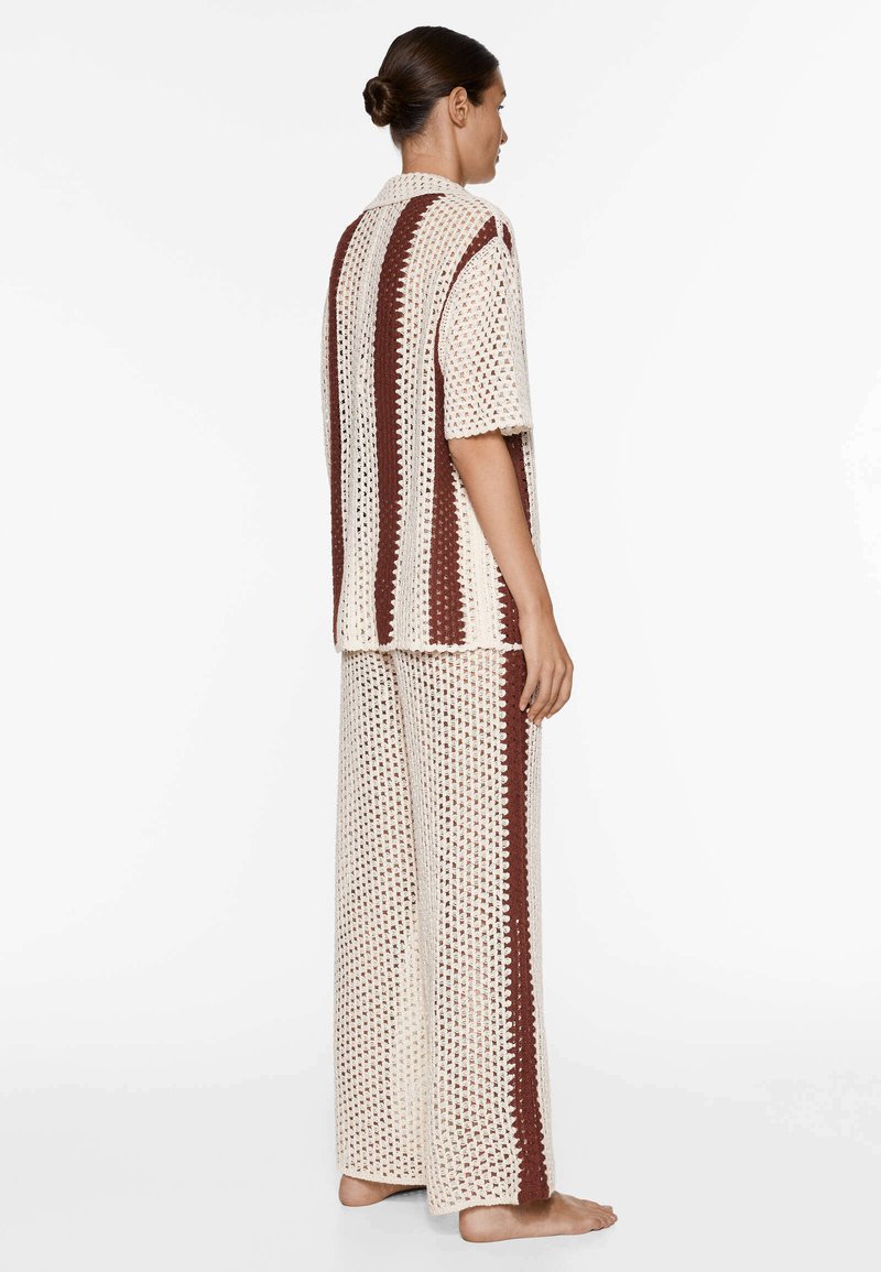 Set in cotone color crema e marrone, composto da top a maniche corte e pantaloni a gamba larga. Tessuto a lavorato a giorno con dettagli a strisce.