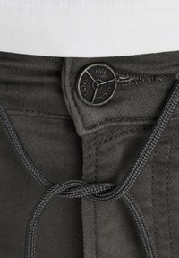Dark gray pants featuring a metal button with "PME Legend Jeans" engraved, and a braided drawstring at the waist for adjustment.