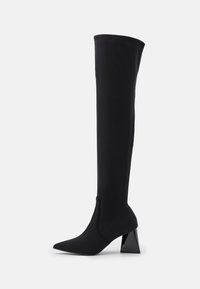 Botas negras por encima de la rodilla, hechas de un material suave y elástico. Cuentan con una punta afilada y un tacón geométrico y brillante.