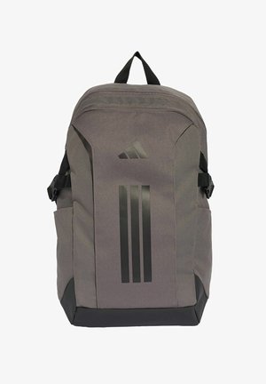 Mochila Adidas gris con diseño negro de tres rayas, bolsillos laterales, correas ajustables y asa superior, en posición vertical sobre fondo blanco.
