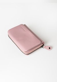 Roze leren portemonnee met een ritssluiting, voorzien van een gladde textuur en ronde hoeken. Inclusief een lus voor bevestiging.