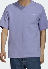 Levandulové bavlněné tričko s krátkým rukávem, volný střih, kulatý výstřih a malá vyšitá značka na prsou. Nosit s džínovými kalhotami.