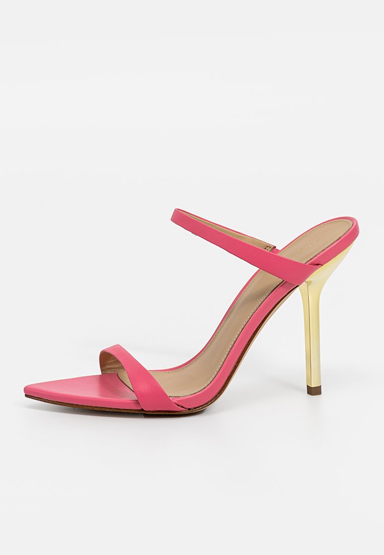 Sandale à talons hauts rose avec un bout pointu, deux fines lanières et un talon aiguille doré brillant sur un fond blanc.