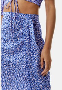 Blue patterned skirt with light pink and darker blue abstract designs. Features a gathered waist and side pockets. Smooth fabric texture.
