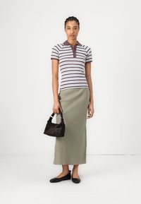 Randig brun och ljusblå polo-tröja, olivgrön kjol, liten svart handväska och svarta ballerina-skor. Slät tyg och figurnära design.