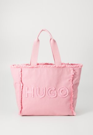 Lyserød mulepose med frynset kant og tykke håndtag, med en tekstureret "HUGO"-logo på forsiden.