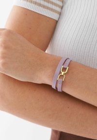 Purple leather bracelet with a gold-tone clasp. Features two slender straps and a textured surface. Simple and modern design.