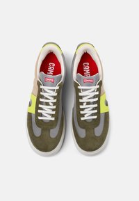 Green and gray sneaker featuring suede and mesh materials, bright yellow accents, and white laces with a red logo on the insole.