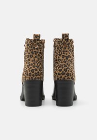 Botas de tobillo con estampado de leopardo, fabricadas con un tejido texturizado, cierre de cremallera y tacón sintético negro. Presenta detalles en tono dorado.
