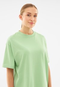 Jasnozielona, oversize T-shirt, krótki rękaw, okrągły dekolt, miękka tekstura, prosty design, bez widocznych wzorów czy akcentów.