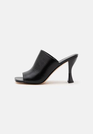 Black open-toe mule with high curved heel and smooth leather upper, shown from the side on a white background.