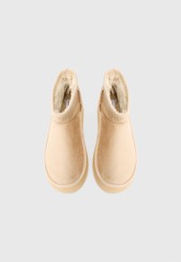 Bež čizme do članaka z mekim baršunastim slojem, podstavkom od umetnog krzna, okruglim vrhom i glatkim gumiranim đonom s suptilnim teksturiranim rubom.