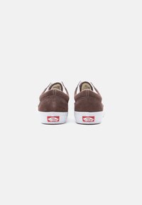 Een paar bruine suède Vans sneakers, van achteren getoond, met witte zolen en een rood "Off The Wall" logo op de hielen.