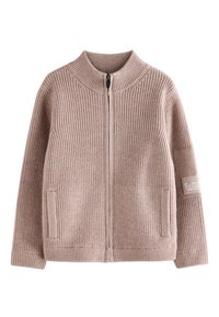 Cardigan beige doux et côtelé avec col montant, fermeture éclair, poches latérales et étiquette en tissu sur la manche gauche.