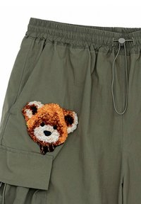 Shorts cargo color caqui con banda elástica en la cintura, que presentan una cara de oso texturizada y bordada en el bolsillo izquierdo.