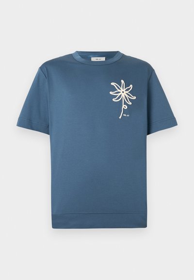 T-shirt azul de mangas curtas com decote redondo e um desenho de flor branca ao lado do peito esquerdo, feito de um tecido macio e respirável.