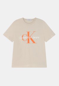 Beżowa koszulka z krótkim rękawem wykonana z bawełny, z dużym pomarańczowym logo "CK" oraz białym napisem "Calvin Klein Jeans" na przedzie.