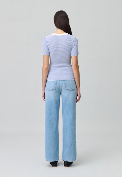 Top a maniche corte a righe blu e bianche, aderente, con scollatura rotonda; abbinato a jeans a gamba larga blu chiaro con tasche posteriori.