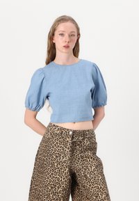 Ljust blå chambray kort topp med puffärmar, parat med hög midja leopardmönstrade vida byxor, som har knappstängning.