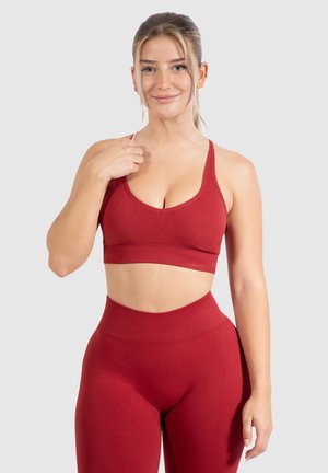 Rode sportbeha met een diepe hals en brede schouderbanden, gecombineerd met hoge taille leggings, beide gemaakt van een gladde, rekbare stof.