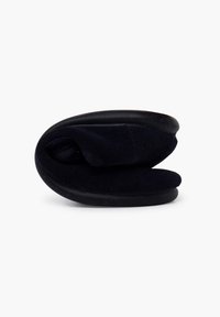 Zapatilla plegable negra hecha de un tejido suave con suela de goma; presenta una forma redondeada y contorneada para mayor comodidad y fácil almacenamiento.