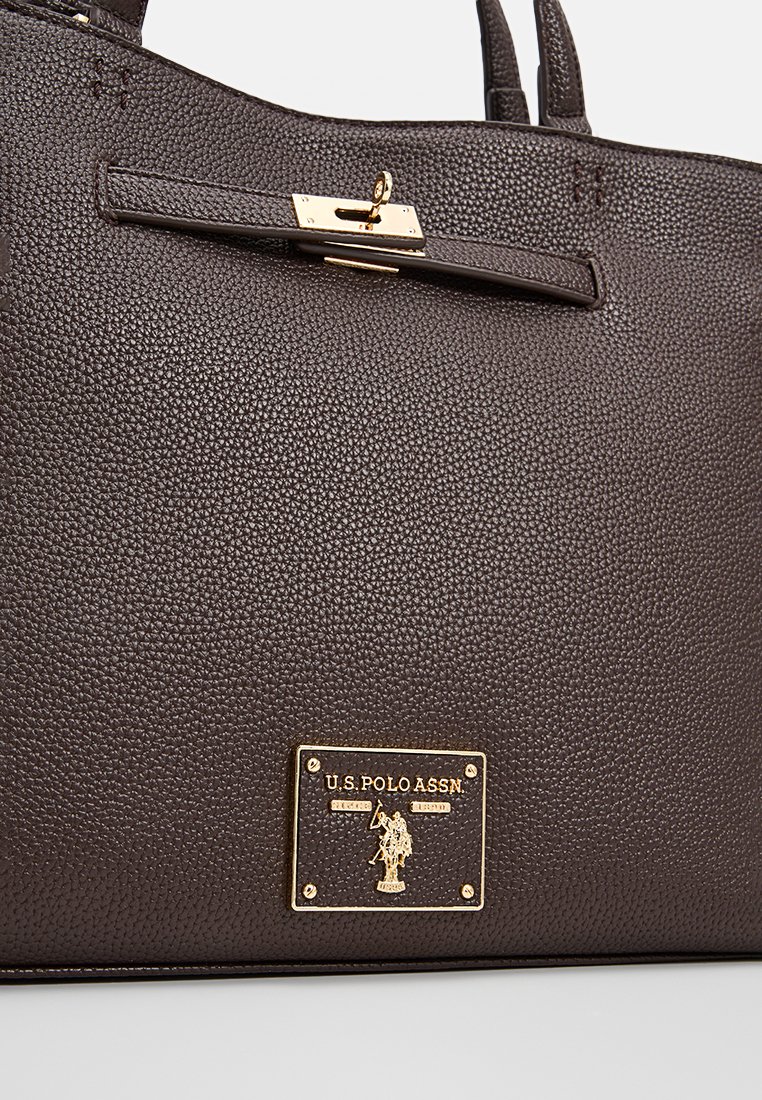 Bolso sintético texturizado de color marrón oscuro, con un cierre de hardware en tono dorado y placa con logo, y asas superiores dobles para llevar.