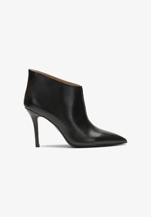 Melnas ādas potītes zābaks ar norādītu pirkstu un stiletto papēdi. Gluda tekstūra ar minimālistisku dizainu un bez redzamiem aksesuāriem vai akcentiem.
