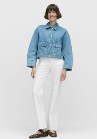 Vaaleansininen farkku cropped-takki pitkillä hihoilla, kaksi etutaskua ja hopeanväriset napit, yhdistetty valkoisiin housuihin ja eläinkuosilla varustettuihin ballerinoihin.