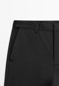 Schwarze maßgeschneiderte Hose aus glattem Stoff, mit flachem Bund und seitlichen Taschen. Gürtelschlaufen und ein sauberer Abschluss am Saum.