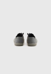 Un paio di scarpe casual grigie con suole beige, viste di spalle, su uno sfondo bianco uniforme.