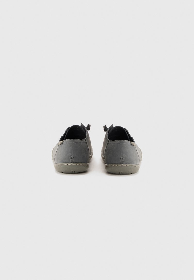 Un paio di scarpe casual grigie con suole beige, viste di spalle, su uno sfondo bianco uniforme.