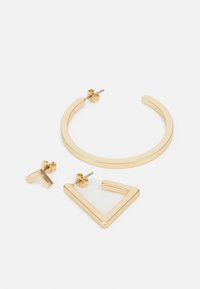 Trois paires de boucles d'oreilles : une créole en or, un triangle géométrique en or et un design de lettre "T" en or, tous présentant une finition métallique polie.