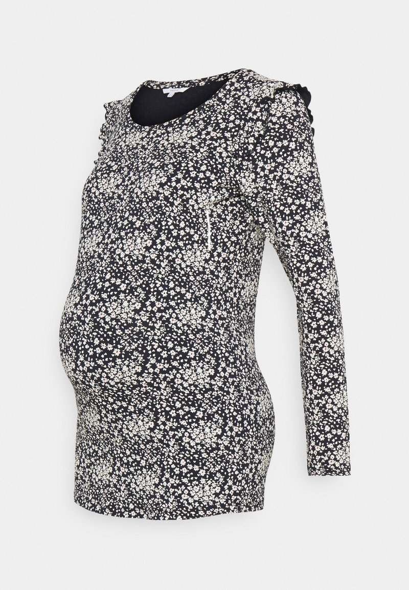 Kojenecký top s dlouhým rukávem v námořnické modři s bílým květinovým vzorem, s volány na ramenou a přiléhavým střihem, aby vyhovoval rostoucímu bříšku.