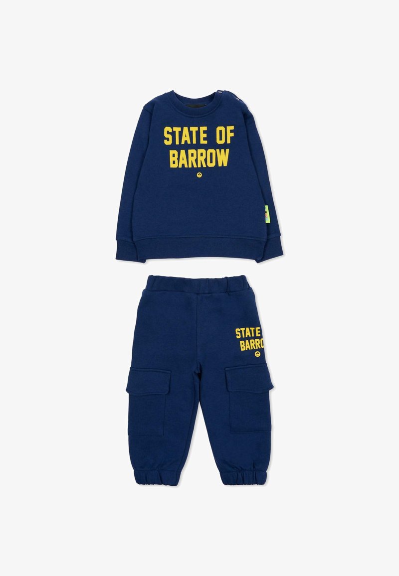 Granatowy sweter z napisem "STATE OF BARROW" w żółtej czcionce, zestawiony z dopasowanymi spodniami cargo z dwiema bocznymi kieszeniami. Miękki materiał.