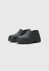 Black rubber clogs with a smooth surface, rounded toes, and a textured sole. Features a low-cut design with no visible laces or hardware.