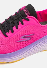 Skechers GOrun shoes feature a bright pink mesh upper, black laces, and a textured purple sole with a yellow accent.