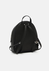 Zwarte leren rugzak met textuur, verstelbare schouderbanden, handvat aan de bovenkant en hardware met zilverkleurige sluitingen op een witte achtergrond.