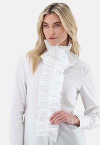 White blouse featuring a ruffled collar with pleats and buttons down the front. Smooth texture, tailored fit, and elegant design.
