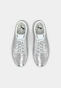 Sølvmetallic Puma sneakers med lyseblå snørebånd, synlig Puma-logo indeni og en mønstret indersål med kædedesign.