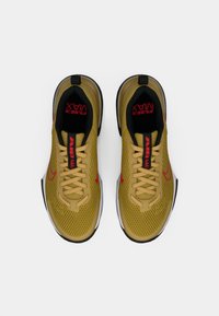 Gule mesh sneakers med sorte og røde detaljer. Har polstret krave, snørebånd lukning og særprægede Air Max branding på snuden.