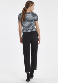 Gestreepte korte mouw top in blauw en grijs met een getailleerde taille, gecombineerd met zwarte rechte jeans en zwarte enkellaarzen.
