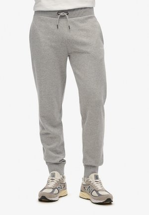 Grey sweatpants with a drawstring waistband, ribbed cuffs, and a soft, brushed texture. Pairing with light-colored sneakers.