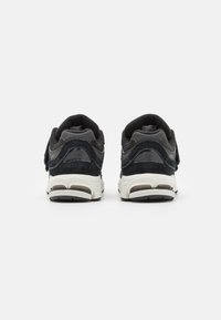 Baskets de sport noires et bleu marine en matériau en daim et en maille, avec un col rembourré, un onglet de talon à boucle et une semelle en caoutchouc blanche.