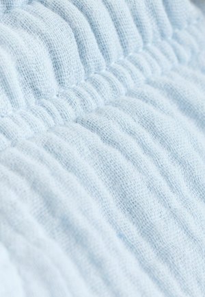 Jasnoniebieska teksturowana tkanina z żebrowanym wzorem, ukazująca miękki, dziergany materiał i subtelne różnice w grubości.