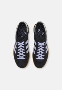 Black suede sneakers with light purple stripes, flat laces, and a gum rubber sole. Features a patterned black insole and smooth black heel.