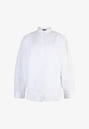 Valge pikkade varrukatega pluus, millel on kõrge krae, peen lillemustriga tikand ja lõdvestunud istuvus.