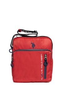 Červená kabelka přes rameno s kapsami na zip v námořnické modři, logem U.S. Polo Assn. a nastavitelným popruhem s černo-bílým vzorem.