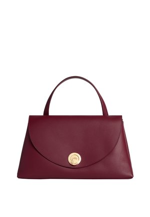 Borsa in pelle bordeaux con una chiusura circolare dorata, caratterizzata da un design strutturato, una parte superiore piatta e una maniglia corta per il trasporto.