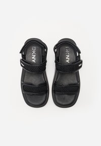 Mustat sandaalit, joissa on kaksi säädettävää Velcro-olkainta, joissa on tekstuurinen verkkokoostumus ja sileä, pehmustettu pohja.